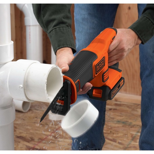 BLACKDECKER BDCR18N cordless reciprocating saw cutting white PVC pipe, close-up action shot.