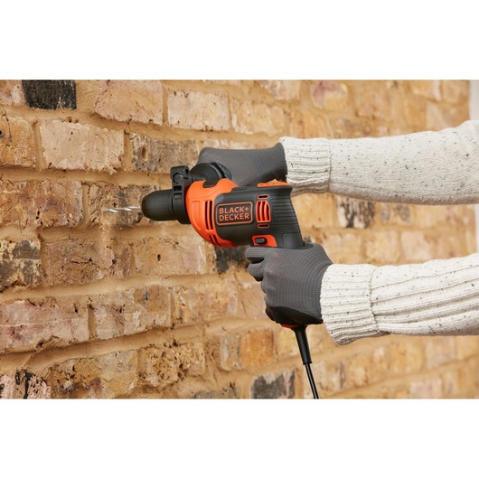 Photo of BLACK+DECKER BEH550 hammer drill in use, drilling into a brick wall.