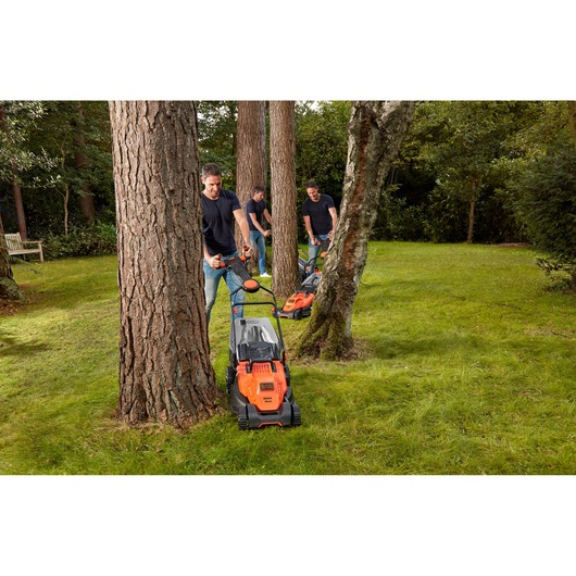 Photo of BLACKDECKER BEMW471ES lawn mower used on grass around trees in a garden setting.