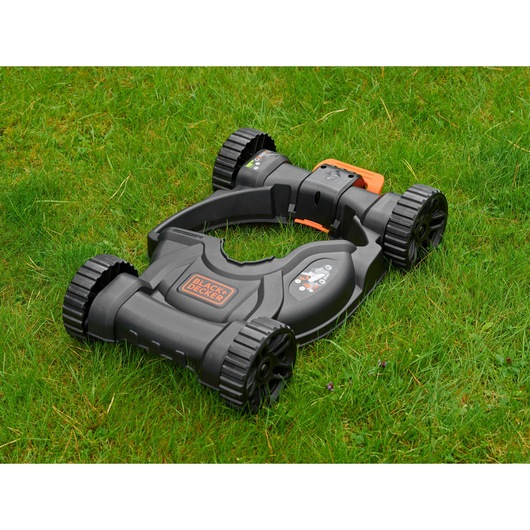 BLACKDECKER CM100 lawn mower accessory in black and orange on grass, side angle.