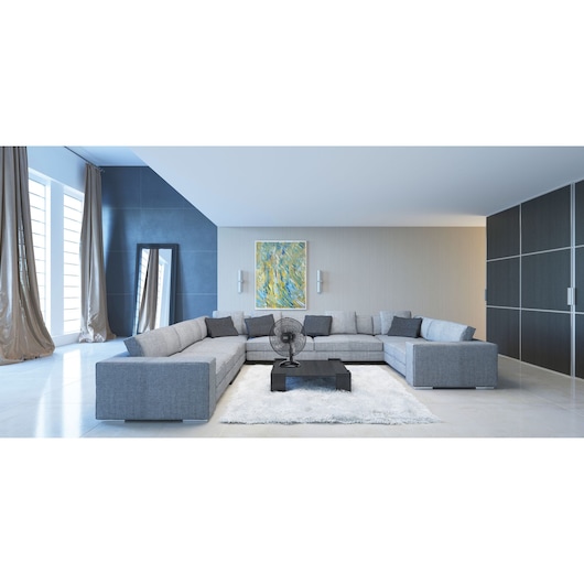 BLACKDECKER FD1620 pedestal fan on black coffee table in modern living room with grey sectional sofa.