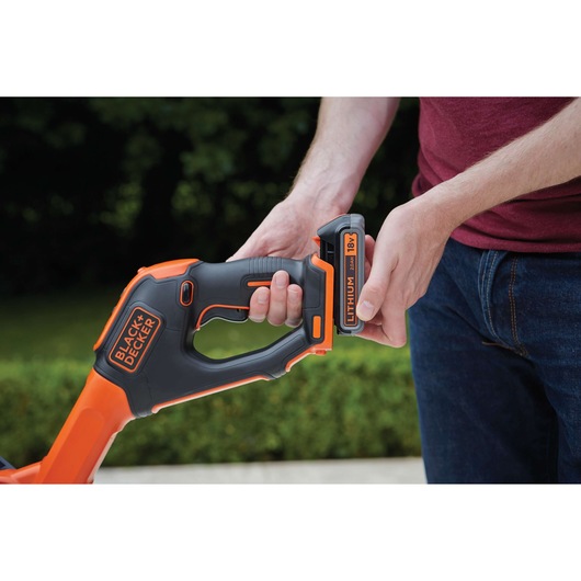 BLACKDECKER STC1820PC grass trimmer, close-up of handle and 18V lithium battery installation outdoors.